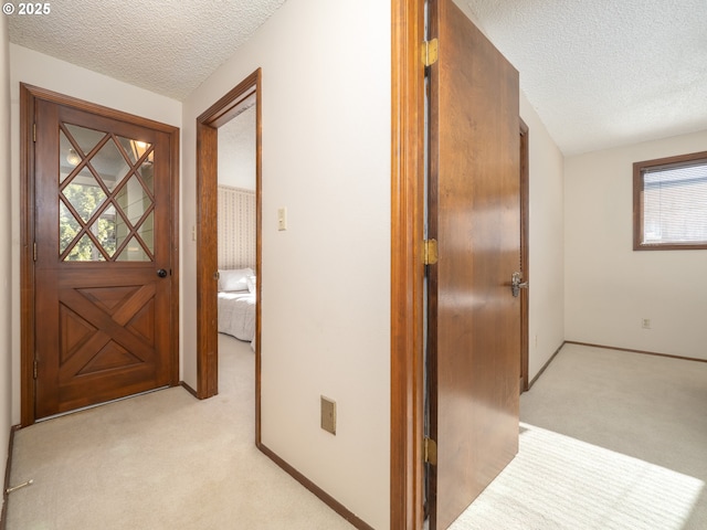 hallway with light carpet and a textured ceiling