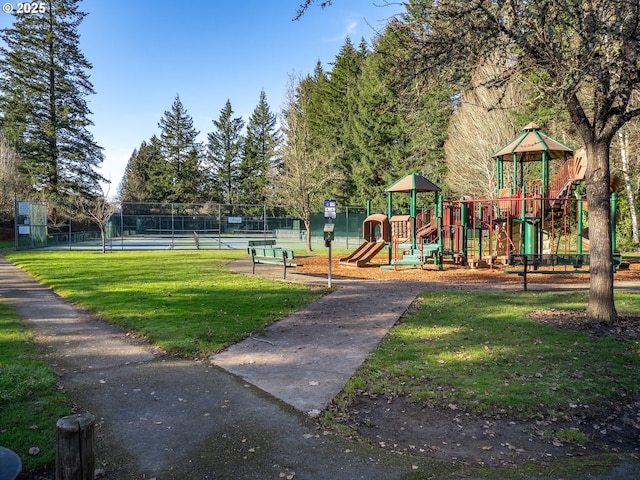 view of play area featuring a lawn and tennis court