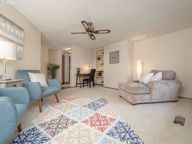 carpeted living room with ceiling fan and a textured ceiling