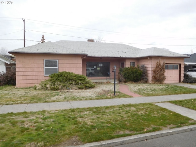 view of front of property with a garage, a chimney, and a front lawn