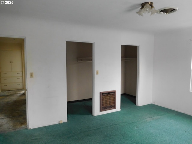 unfurnished bedroom with heating unit, a spacious closet, and carpet flooring