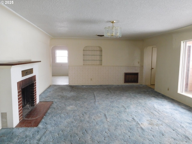 unfurnished living room with carpet, a brick fireplace, and a textured ceiling