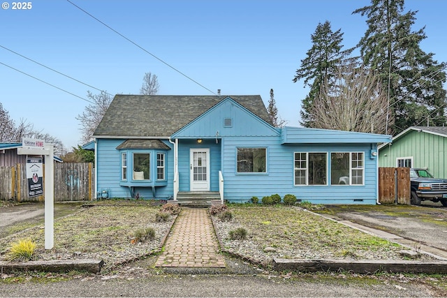 bungalow-style home with crawl space, a shingled roof, and fence