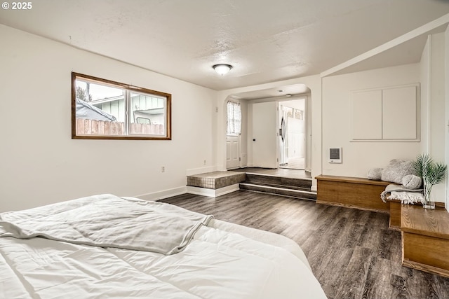 bedroom with heating unit, dark wood-style floors, baseboards, and a textured ceiling