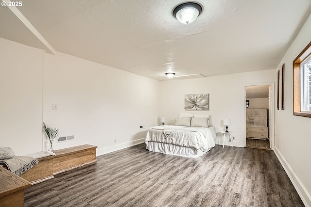 bedroom with baseboards, visible vents, dark wood finished floors, and a textured ceiling