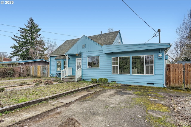 bungalow with crawl space, a shingled roof, fence, and board and batten siding