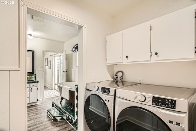 laundry room featuring cabinet space, light wood-style floors, and washing machine and clothes dryer