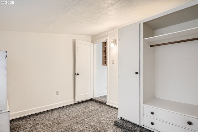 unfurnished bedroom with baseboards, dark colored carpet, and a textured ceiling