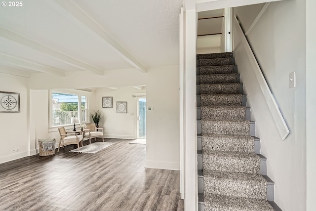 stairs with baseboards, beamed ceiling, and wood finished floors