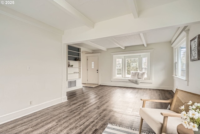 unfurnished room featuring beam ceiling, visible vents, baseboards, and wood finished floors