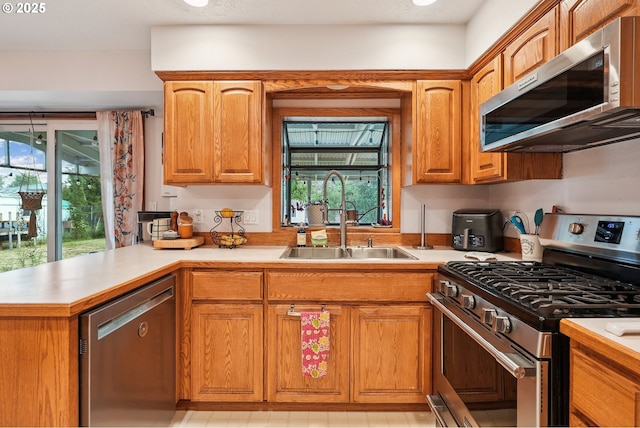 2235 SE 185th Ave, Portland, OR 97233 - kitchen featuring appliances with stainless steel finishes, light countertops, brown cabinets, and a peninsula