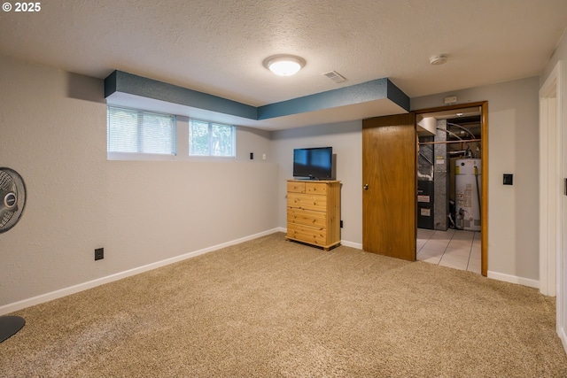 unfurnished bedroom featuring gas water heater, carpet floors, a textured ceiling, baseboards, and a spacious closet
