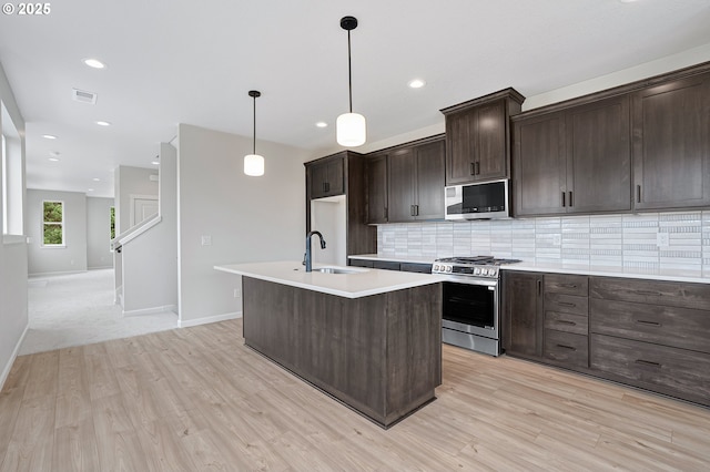 4636 SE 2nd St, Gresham, OR 97080 - kitchen featuring gas range, white microwave, tasteful backsplash, dark brown cabinetry, and light wood finished floors