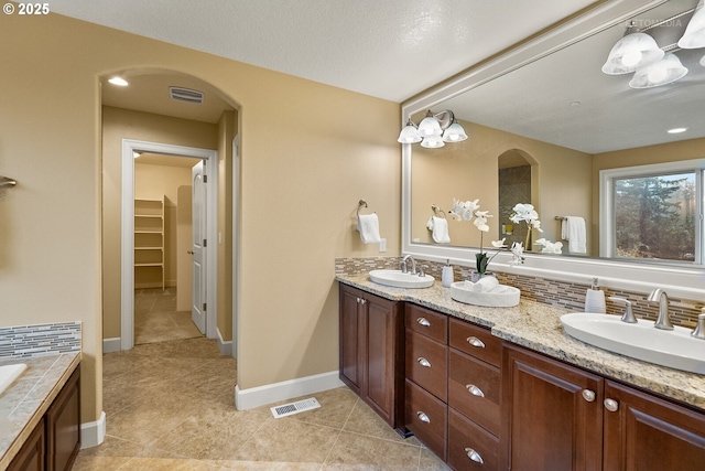 bathroom with a bathing tub, decorative backsplash, and vanity