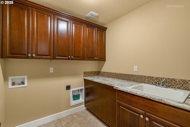 clothes washing area featuring a textured ceiling, cabinets, electric dryer hookup, sink, and washer hookup