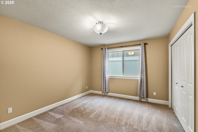 unfurnished bedroom featuring carpet floors, a textured ceiling, and a closet