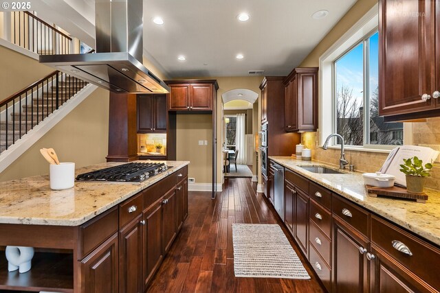 kitchen featuring light stone countertops, appliances with stainless steel finishes, island range hood, and dark hardwood / wood-style floors