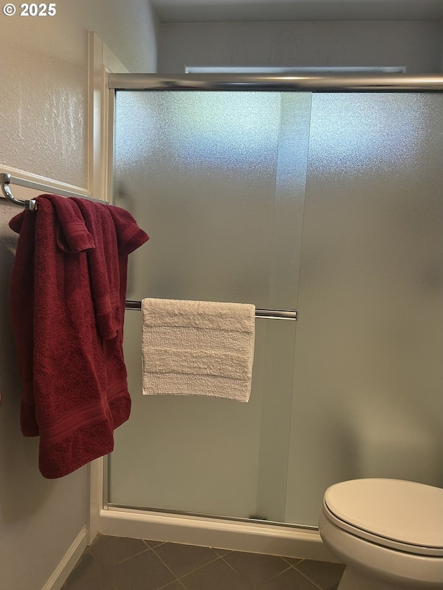 full bath featuring a shower stall, tile patterned flooring, toilet, and baseboards