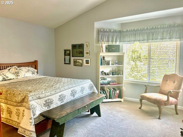 carpeted bedroom with lofted ceiling and baseboards