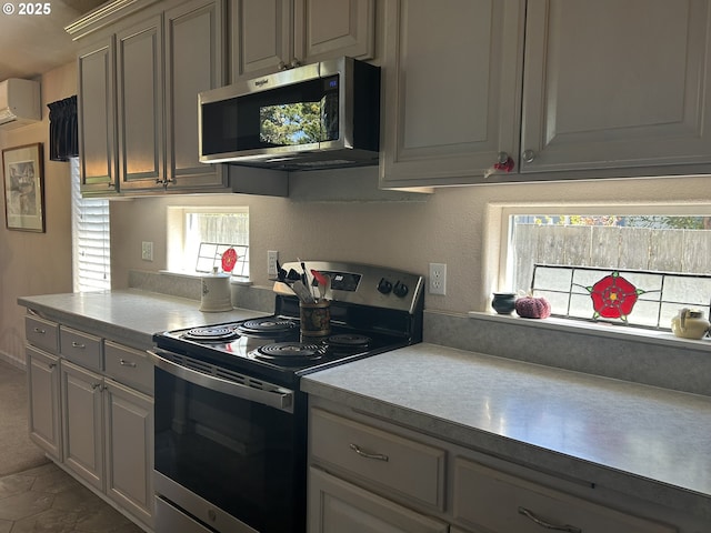 kitchen with a wall mounted air conditioner, light countertops, stainless steel appliances, and gray cabinets