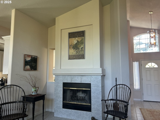 tiled foyer entrance with a fireplace, a chandelier, lofted ceiling, and baseboards
