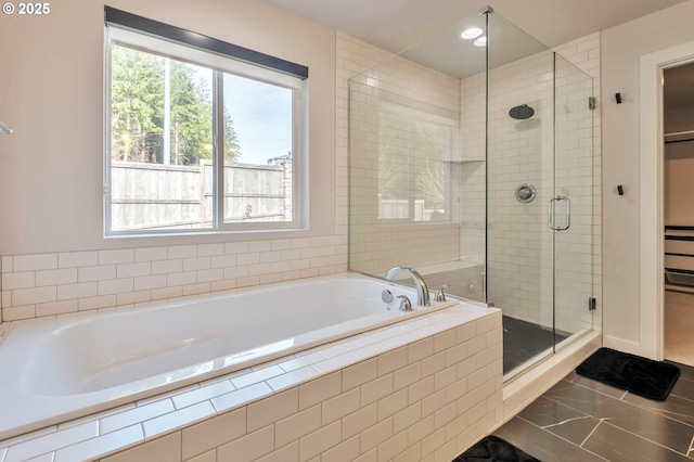 bathroom featuring a stall shower, plenty of natural light, a spacious closet, and a bath