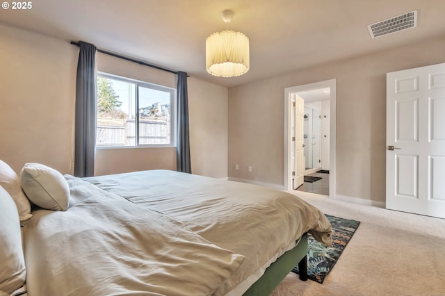 carpeted bedroom featuring connected bathroom, visible vents, and baseboards