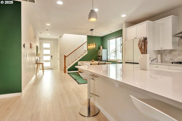 kitchen with pendant lighting, light wood finished floors, plenty of natural light, and white cabinets