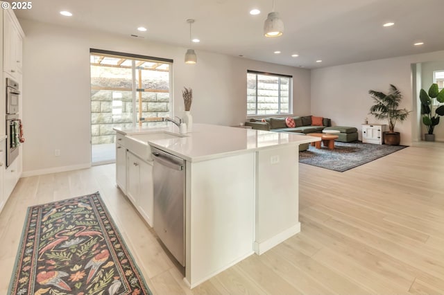 kitchen featuring light wood-style flooring, recessed lighting, stainless steel appliances, a sink, and white cabinets