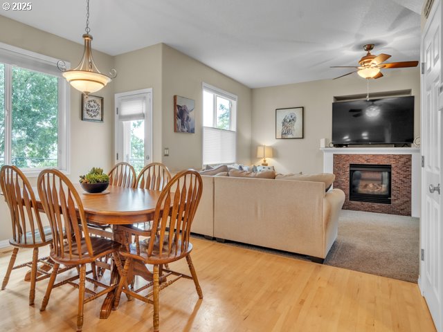 dining space with a ceiling fan, light wood finished floors, and a glass covered fireplace