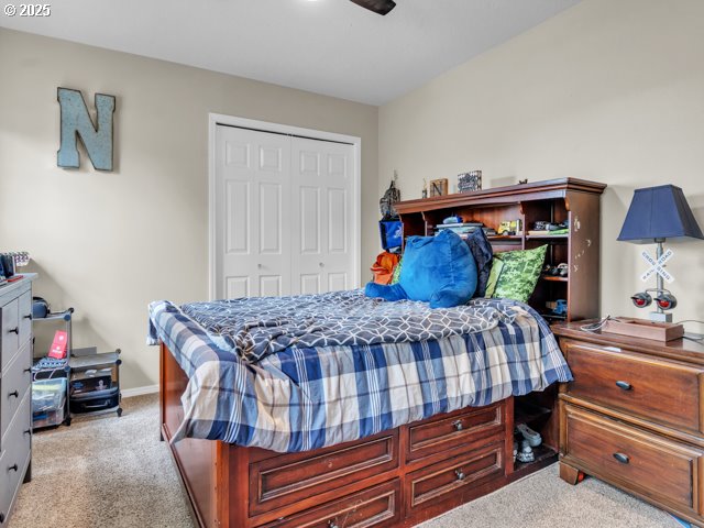 carpeted bedroom with a closet, ceiling fan, and baseboards