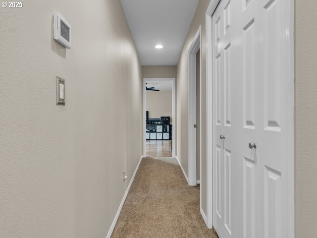 hall featuring light colored carpet, baseboards, and recessed lighting