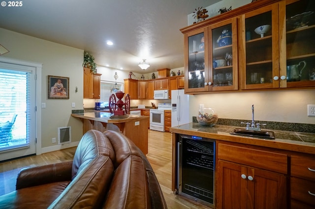 kitchen featuring beverage cooler, white appliances, a sink, brown cabinets, and light wood-type flooring