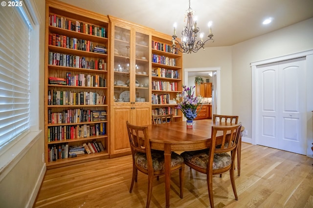 dining room with light wood-style flooring, a chandelier, and baseboards