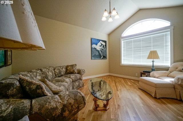 living area featuring lofted ceiling, wood finished floors, a chandelier, and baseboards