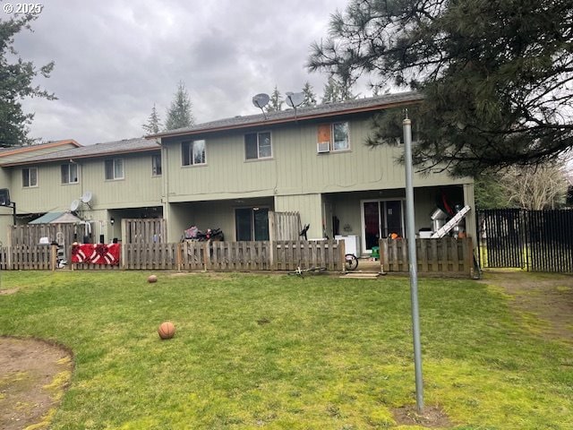 back of house featuring fence and a lawn