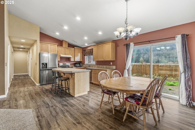 dining room featuring vaulted ceiling, a chandelier, and dark hardwood / wood-style floors