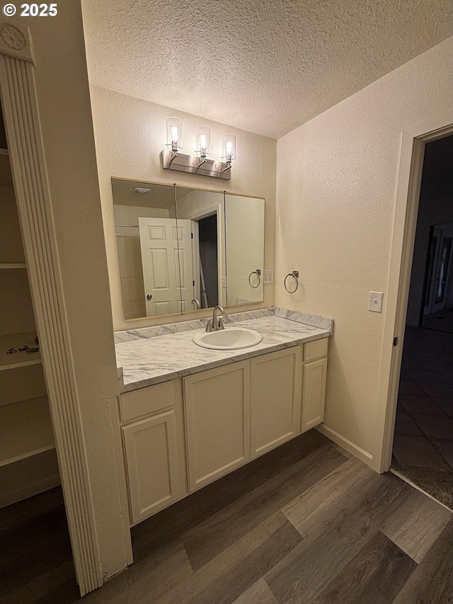 bathroom with vanity, a closet, a textured wall, wood finished floors, and a textured ceiling