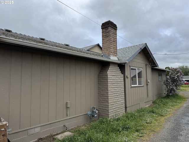 view of side of home with a chimney and roof with shingles