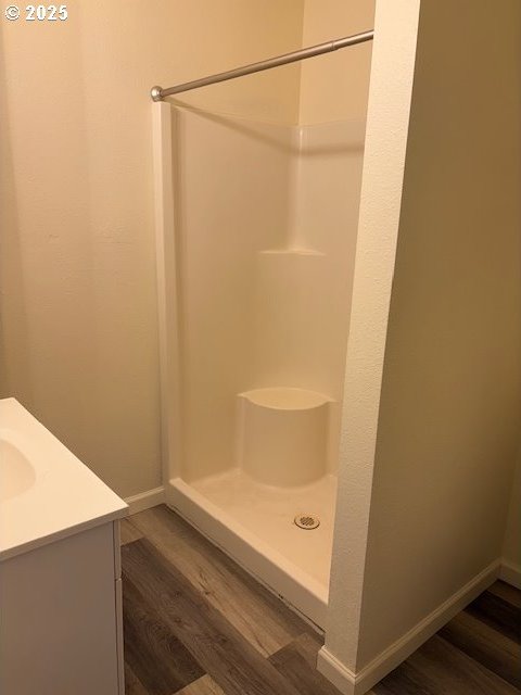 bathroom with vanity, baseboards, wood finished floors, and a stall shower