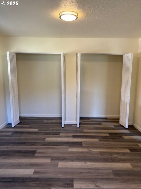unfurnished bedroom featuring a closet, baseboards, and dark wood-type flooring