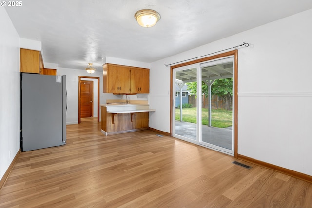1897 Chelan St, Keizer, OR 97303 - kitchen with freestanding refrigerator, brown cabinetry, light countertops, and a peninsula