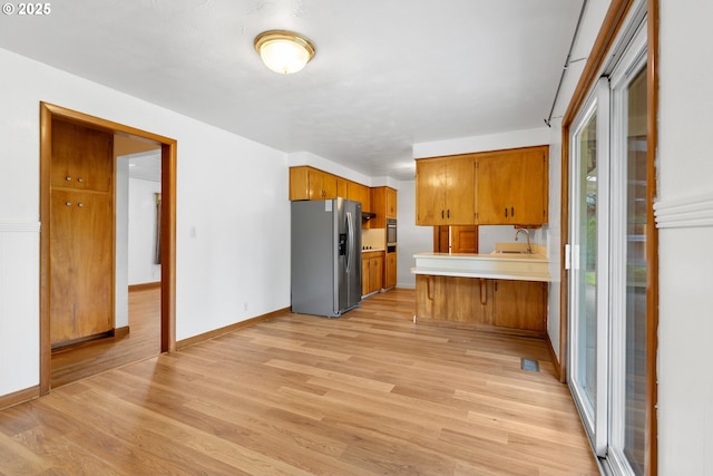 1897 Chelan St, Keizer, OR 97303 - kitchen with stainless steel appliances, a sink, brown cabinets, a peninsula, and light countertops