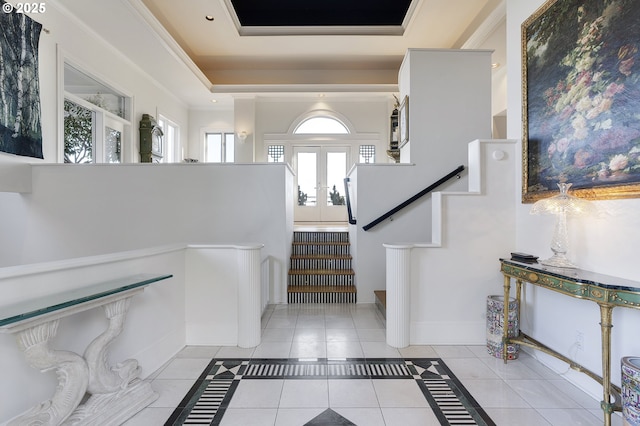 tiled foyer entrance with a tray ceiling, crown molding, and french doors