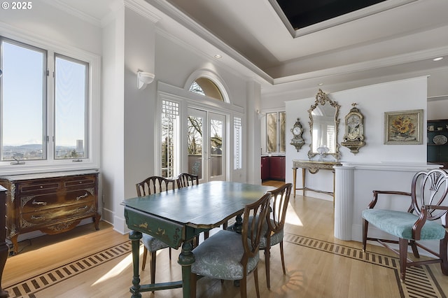 dining area with light wood-type flooring, crown molding, and a healthy amount of sunlight