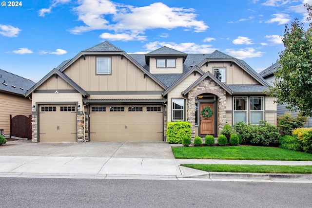 craftsman inspired home featuring a front yard, driveway, roof with shingles, stone siding, and board and batten siding