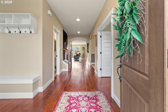 foyer with arched walkways, recessed lighting, dark wood-type flooring, and baseboards