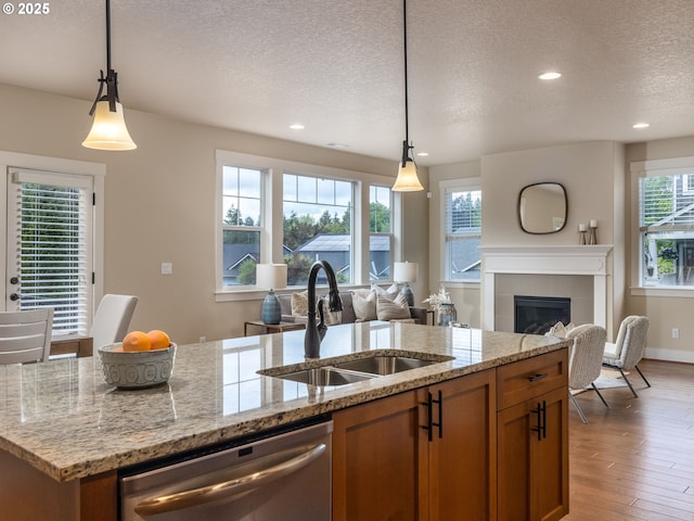 14420 SW Equestrian Ln, Beaverton, OR 97008 - kitchen featuring dishwasher, a sink, a textured ceiling, open floor plan, and brown cabinets