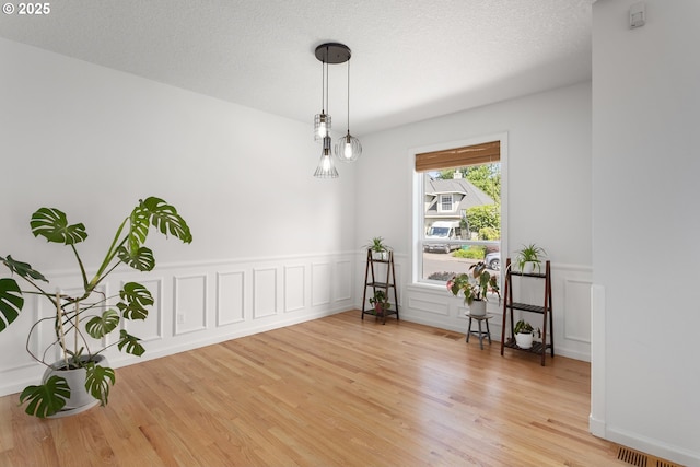 12453 SW Sheldrake Way, Beaverton, OR 97007 - empty room featuring light wood-style flooring, wainscoting, and a decorative wall