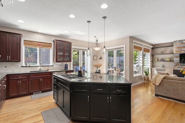12453 SW Sheldrake Way, Beaverton, OR 97007 - kitchen featuring open floor plan, light wood finished floors, stainless steel gas stovetop, a sink, and backsplash